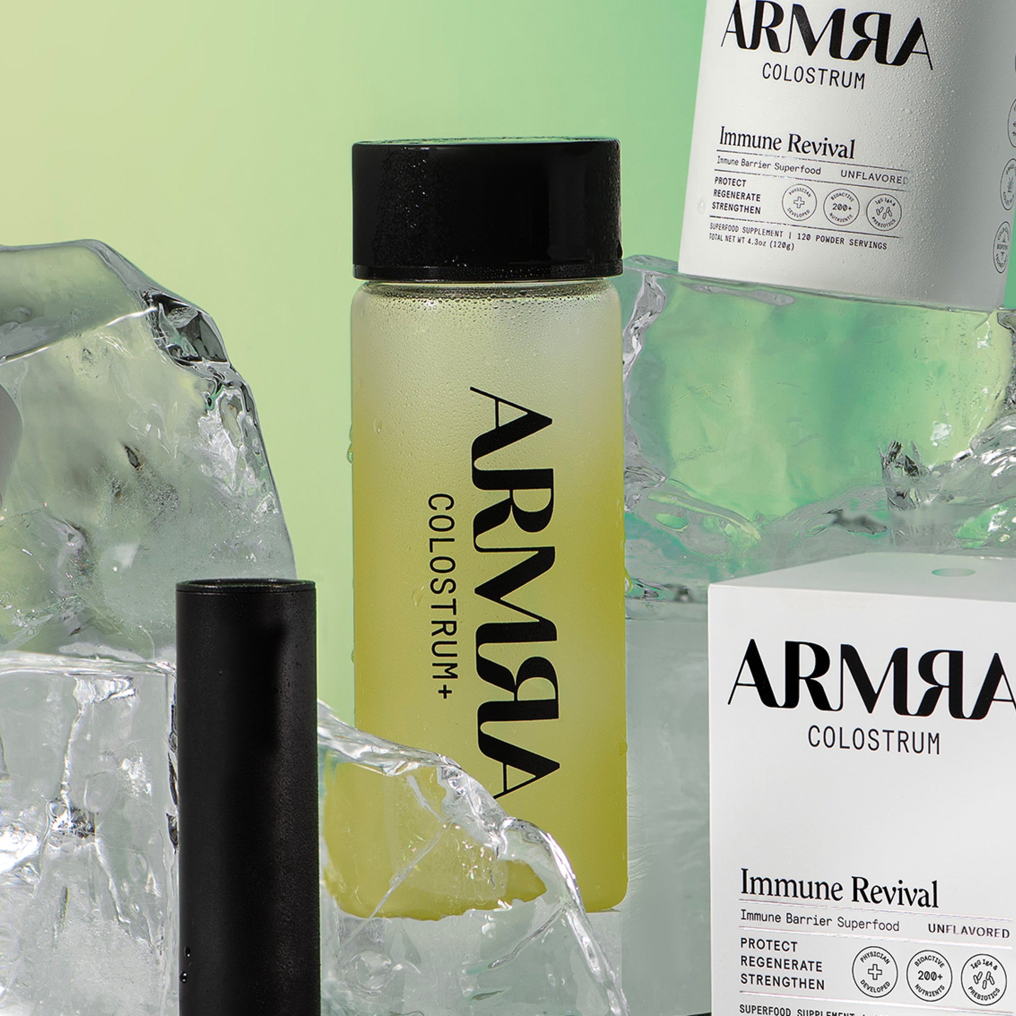 Glass water bottle with black lid and "ARMRA Colostrum+" logo surrounded by blocks of ice and boxes of ARMRA Colostrum Immune Revival