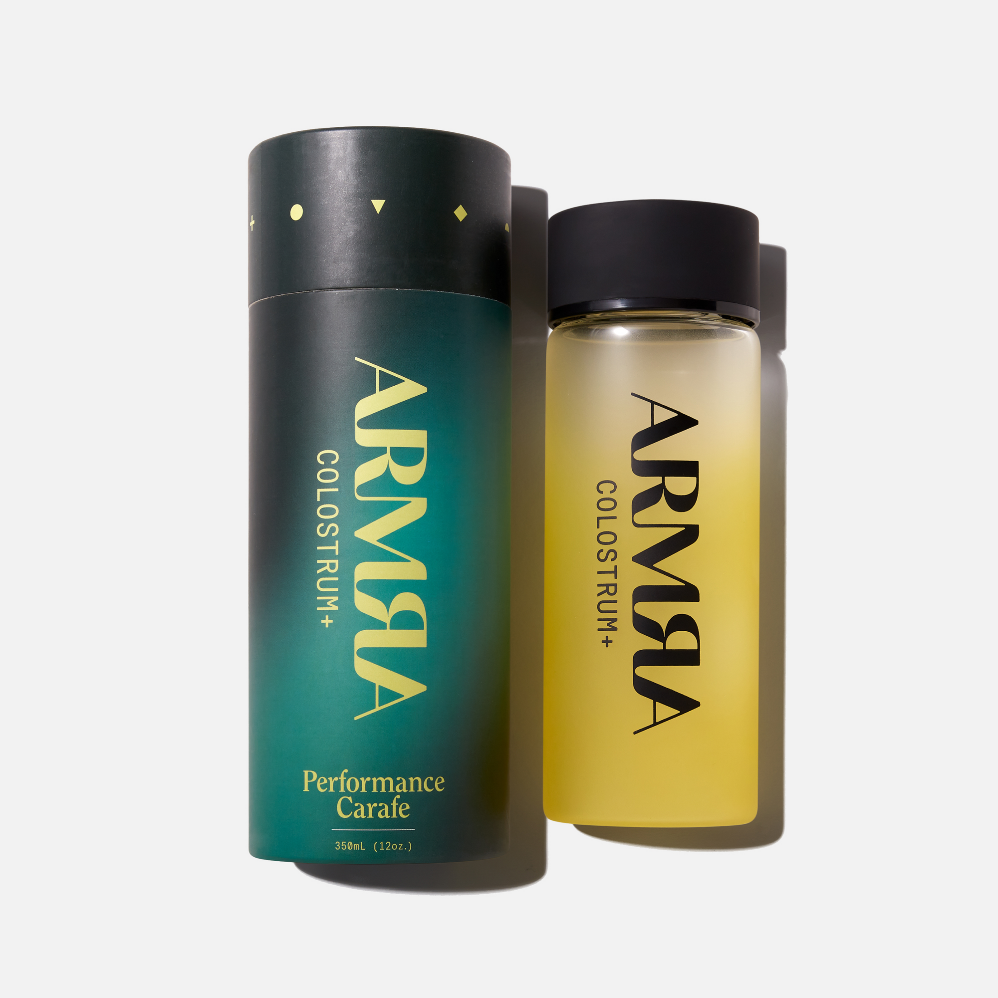 Cylindrical packaging for Water Bottle with “ARMRA Colostrum+“ logo laying next to a glass Water Bottle with a yellow gradient with “ARMRA Colostrum+“ logo