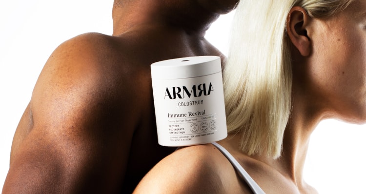man and woman back to back with white ARMRA jar of Immune Revival product on the woman's shoulder