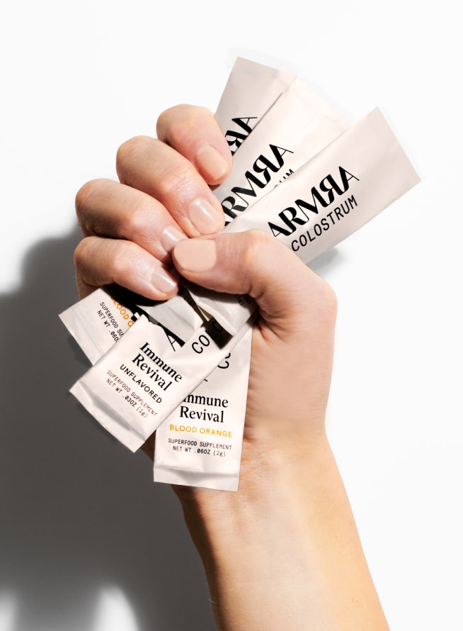 Hand holding ARMRA Sachets for the Immune Revival Product