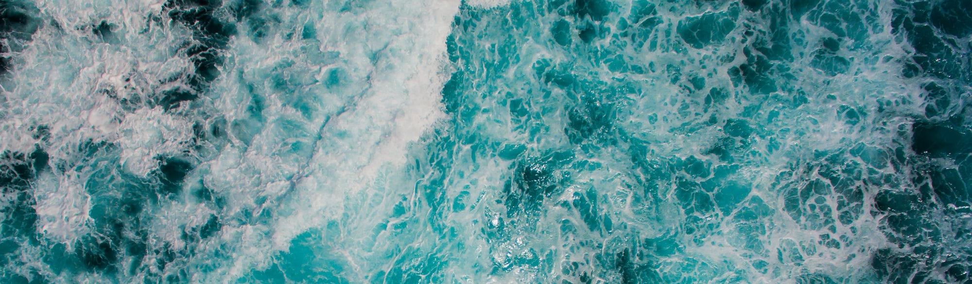 A photograph of water taken from above with shades of blue and white wave details