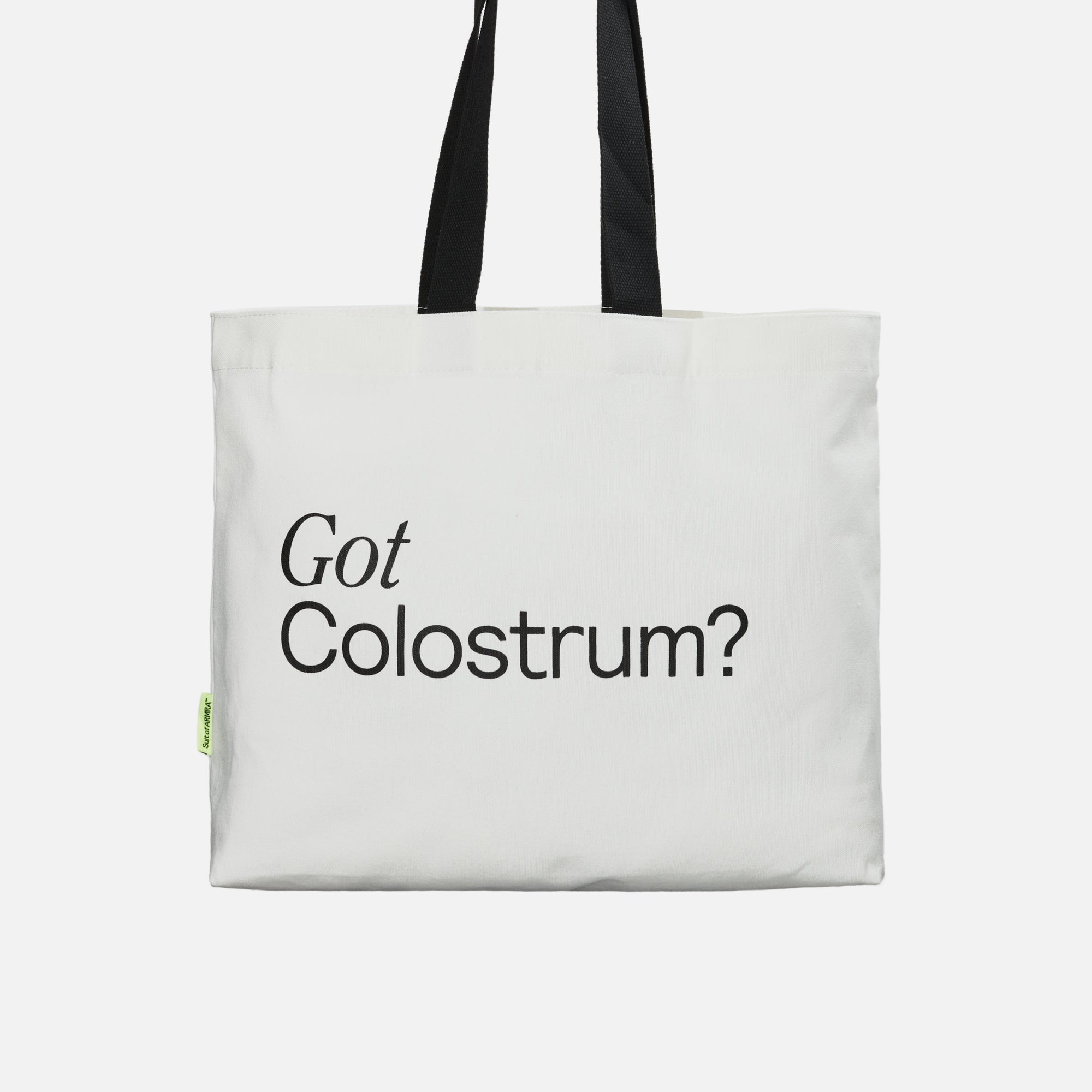 Back of white tote bag with black handles hanging with black text “Got Colostrum”